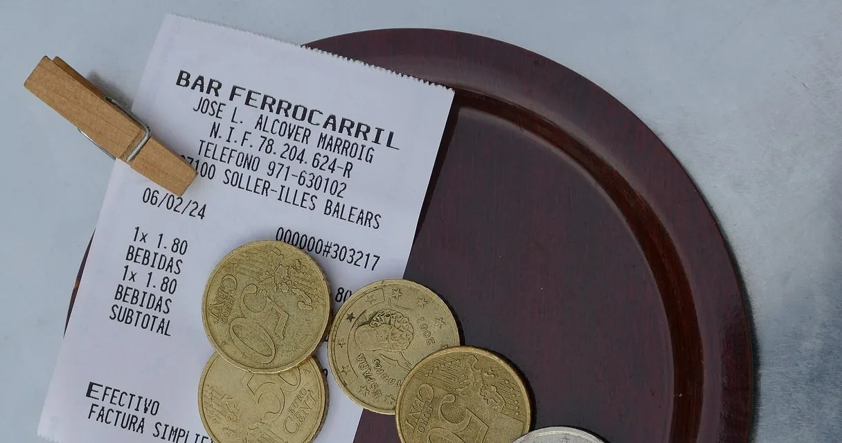 Ticket de un bar junto a monedas de euro