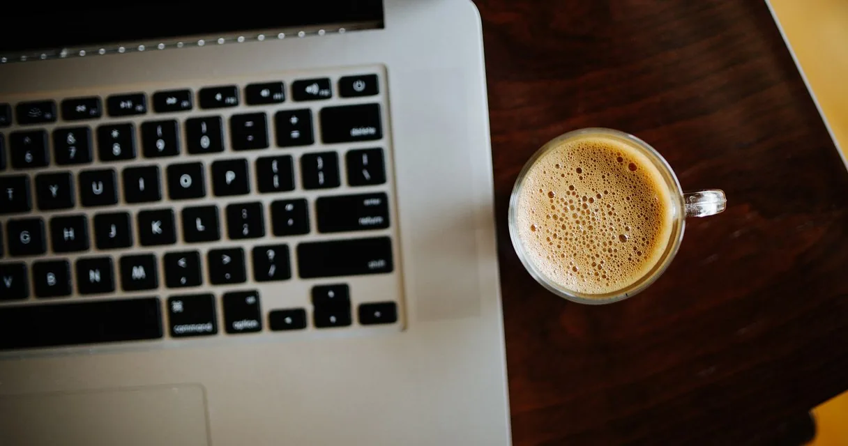Teclado de portátil y taza de café en un escritorio